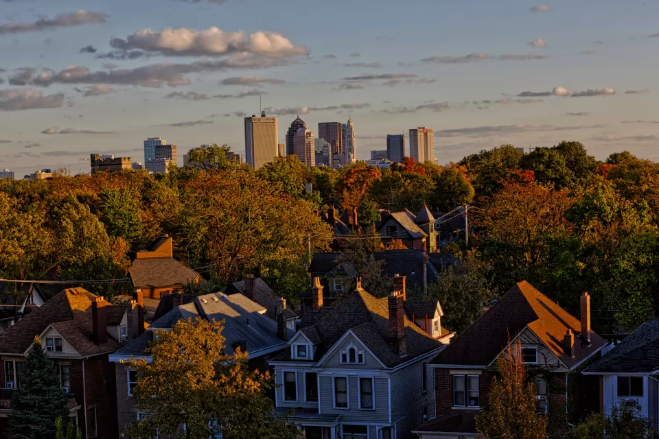 View of homes nestled among green trees with Columbus, Ohio skyline in background